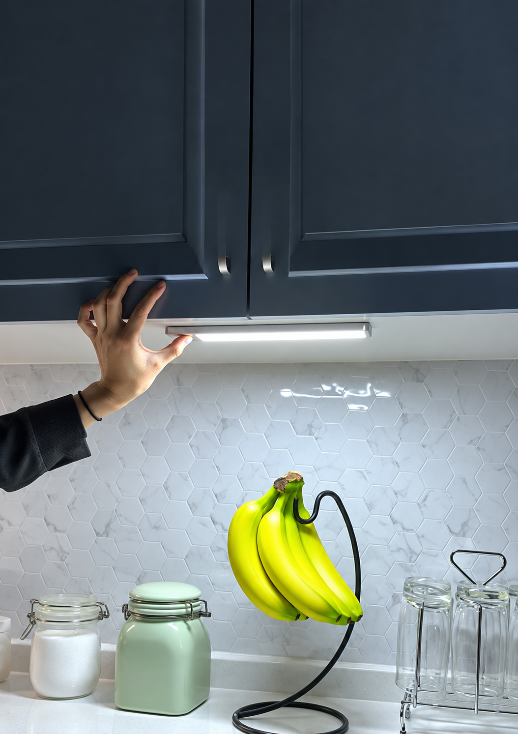 A hand positions one glowing light bar beneath dark kitchen cabinets, with the full bar visible.