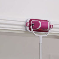 Pink-and-white flat scrubber on an extension pole reaching a high wall edge beside white cornice trim.